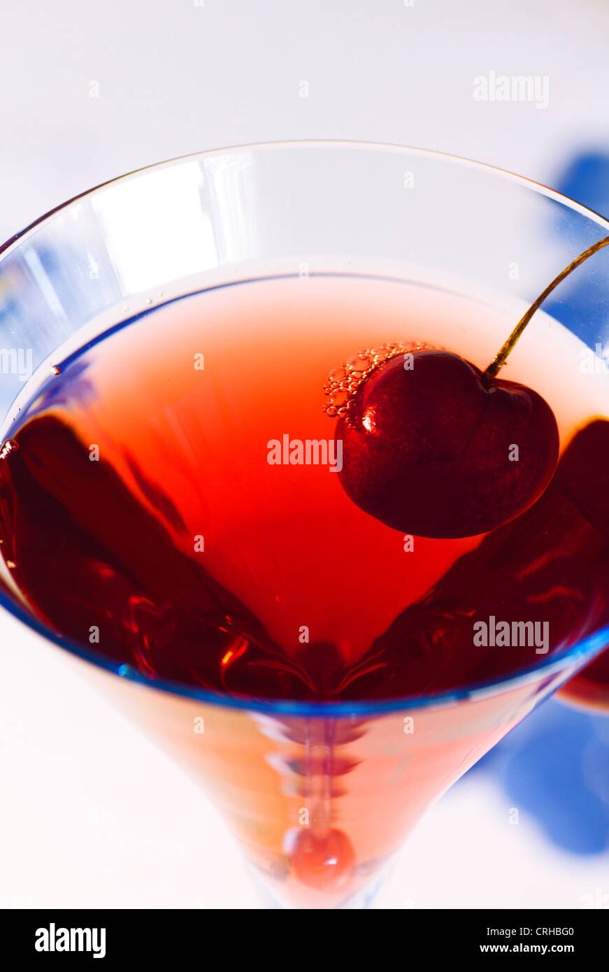 Close-up of Baccarat Blue glassware with Red fruit juice and Red Cherry on the Rim Stock Photo