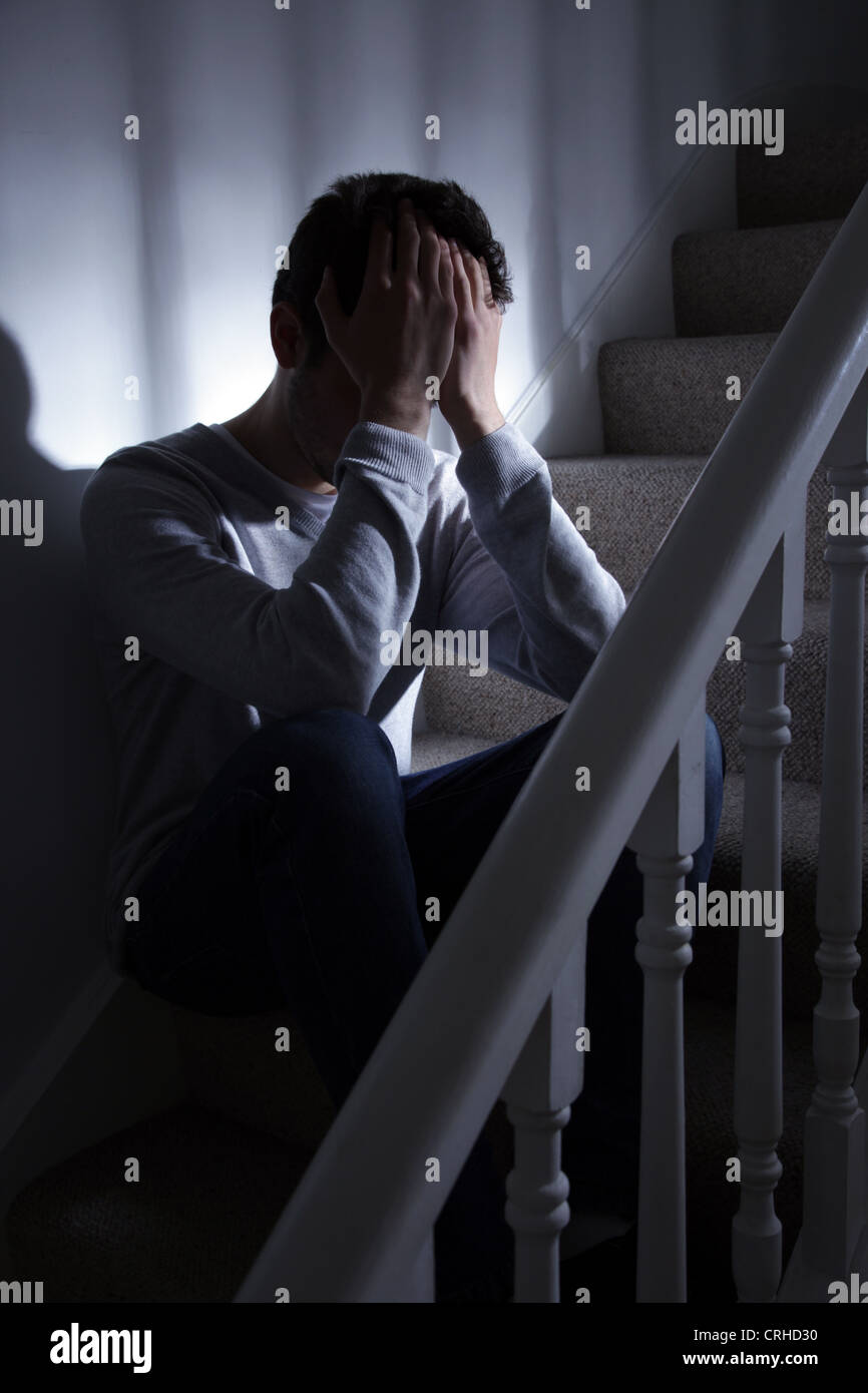 Young man sitting on the stairs with his hands covering his face. Stock Photo