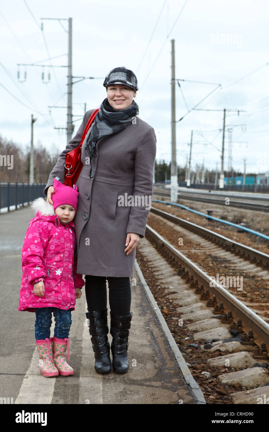 Happy mother and sad small daughter standing on railway station platform. Caucasian Russian people, Russia Stock Photo