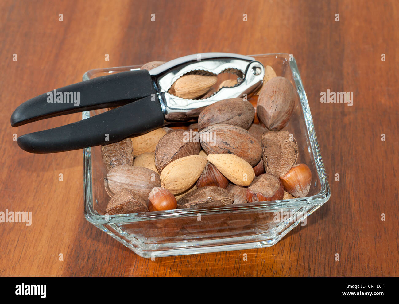Assorted nuts in a glass bowl on a rich brown wooden table Stock Photo