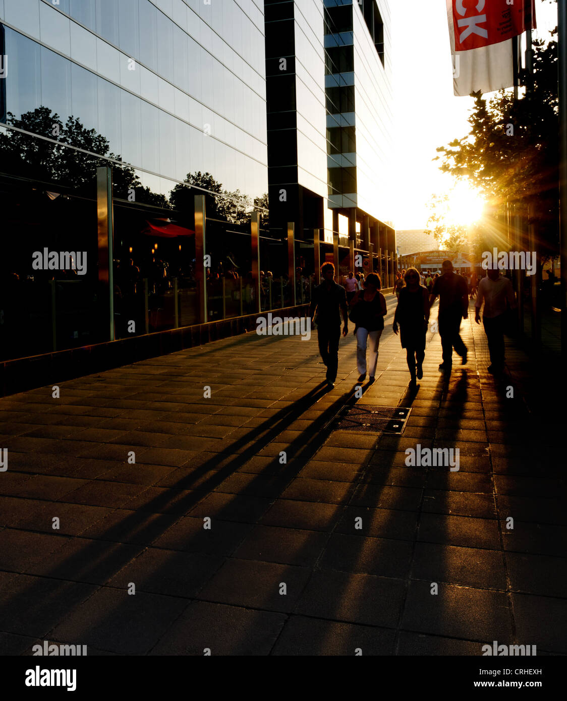 Long shadows of people walking in town at sunset Stock Photo