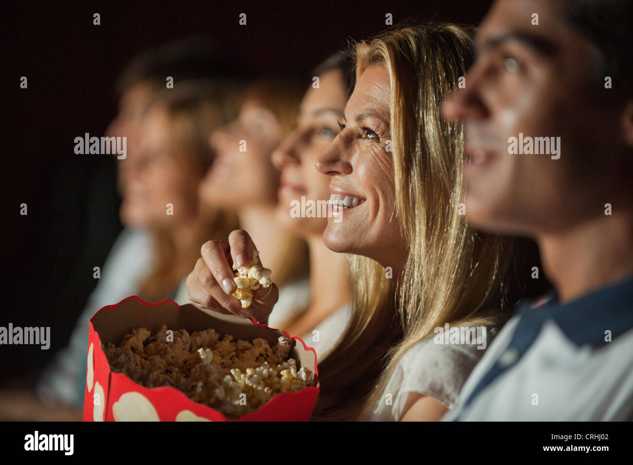 Woman eating popcorn while watching movie in theater Stock Photo