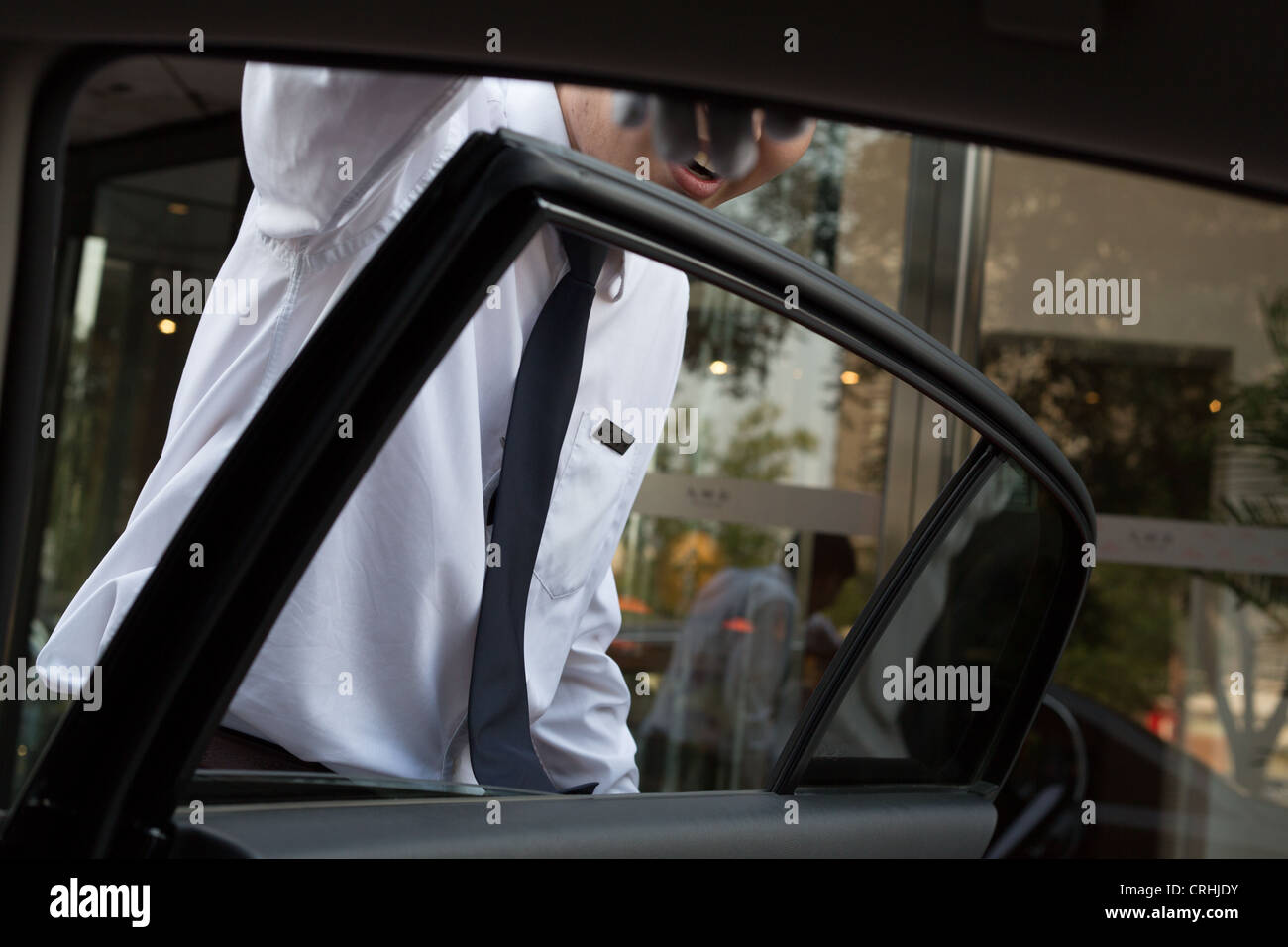 Hotel bellboy opening car door for passenger in Beijing, China Stock
