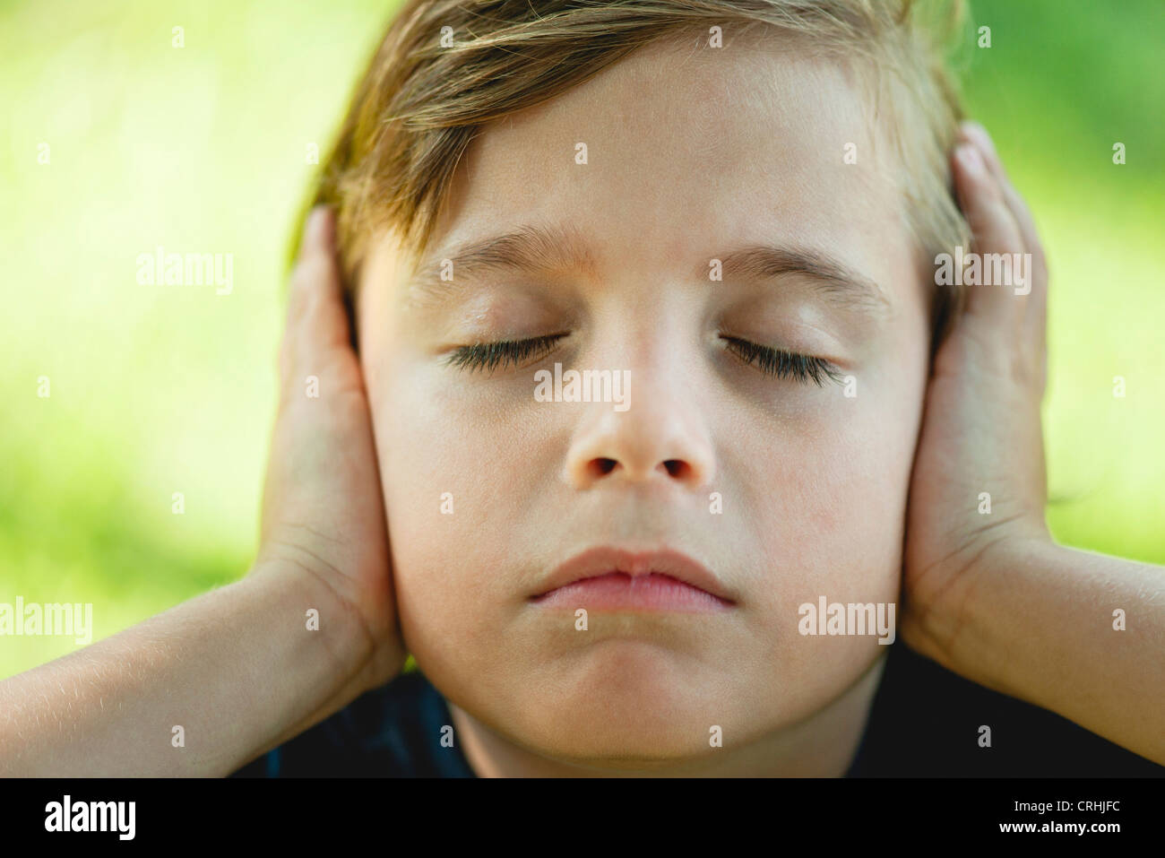 Boy covering ears with hands, eyes closed Stock Photo Alamy