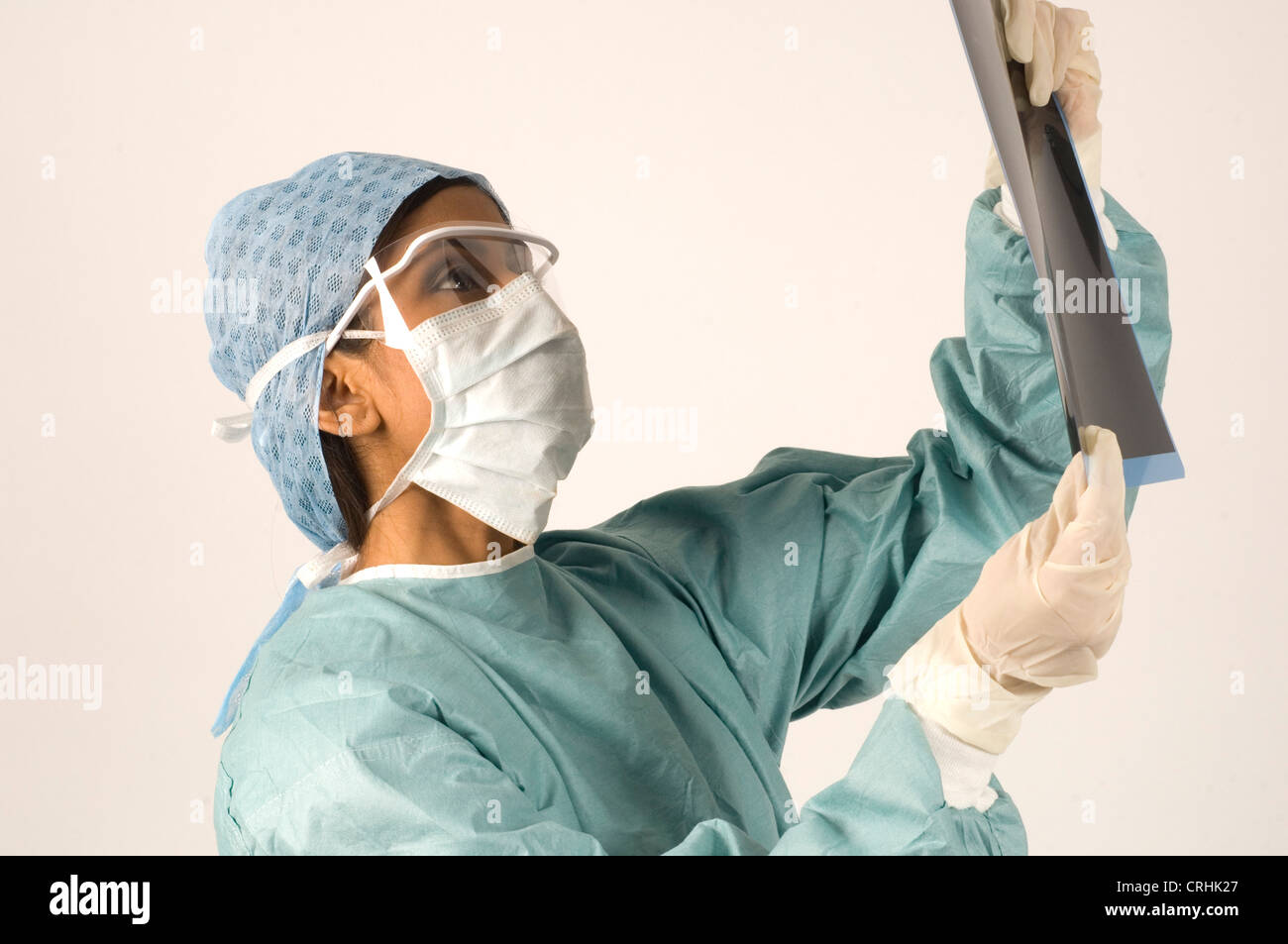 A young female surgeon examines a set of x-rays prior to surgery. Stock Photo