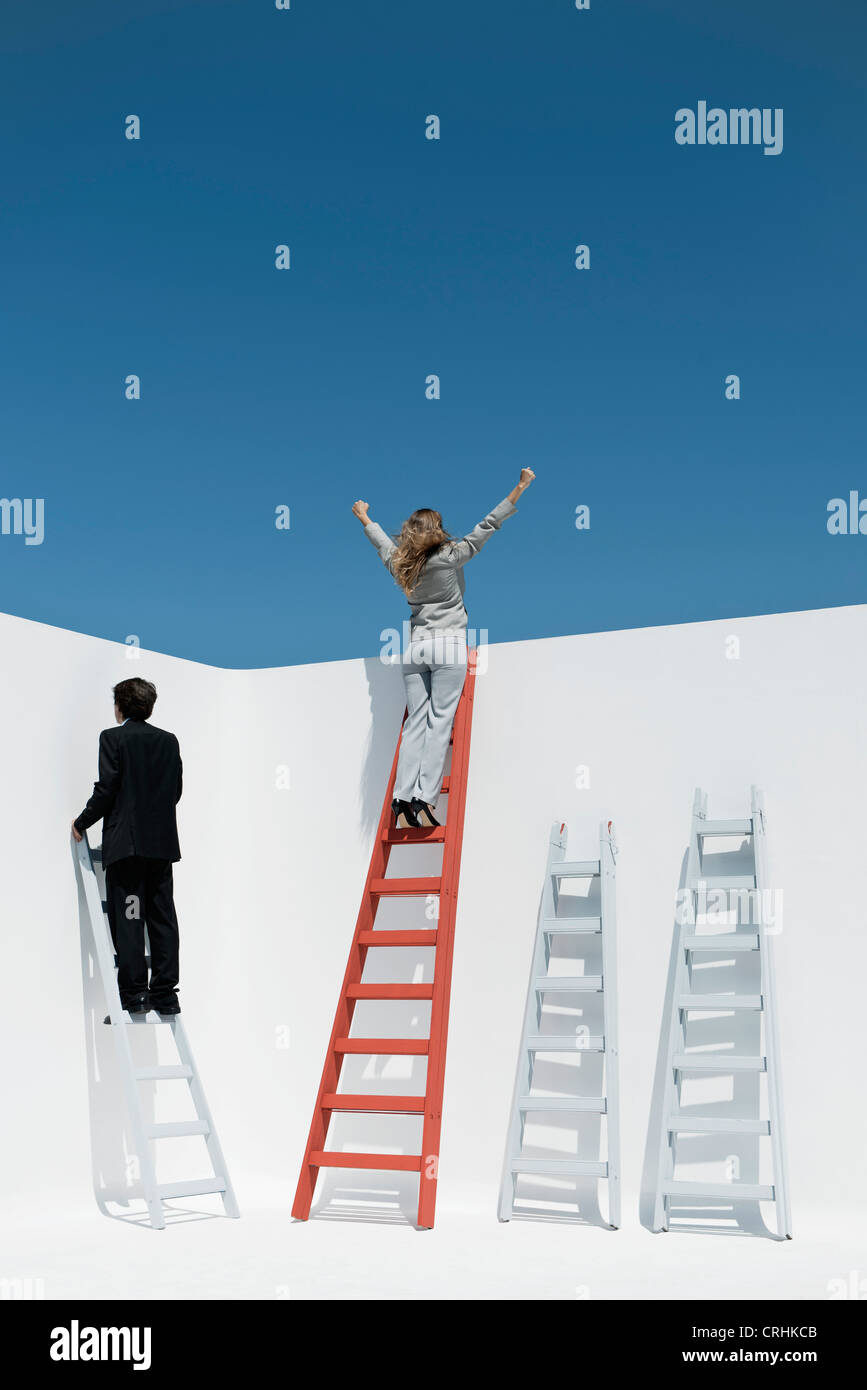 Businesswoman standing at top of ladder with arms raised in air Stock Photo