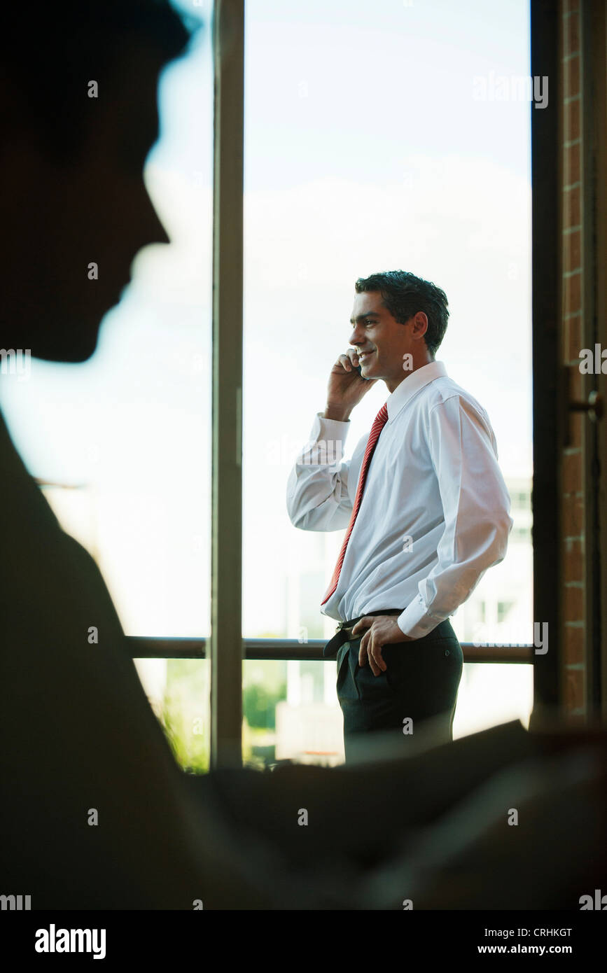 Silhouette of businessman using cell phone by window Stock Photo