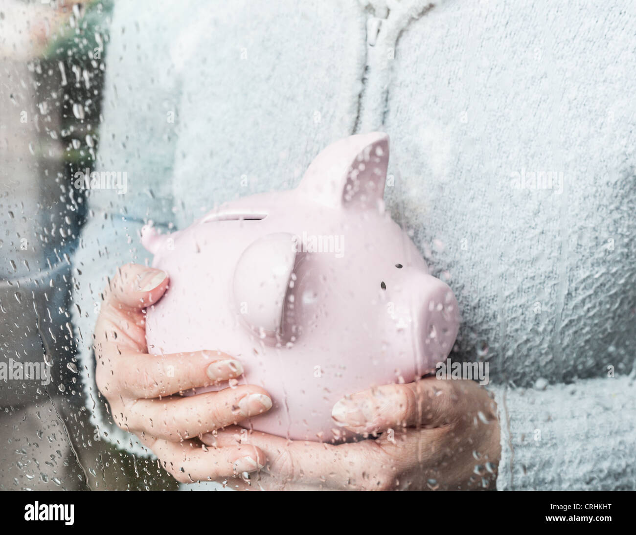 Woman with piggy bank at rainy window Stock Photo