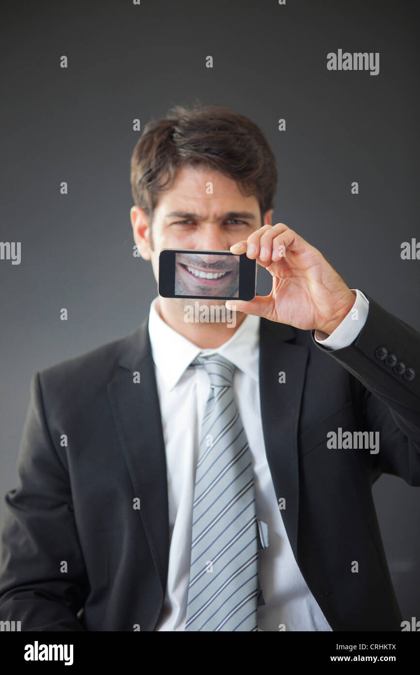 Man holding up smartphone displaying image of his own smile Stock Photo