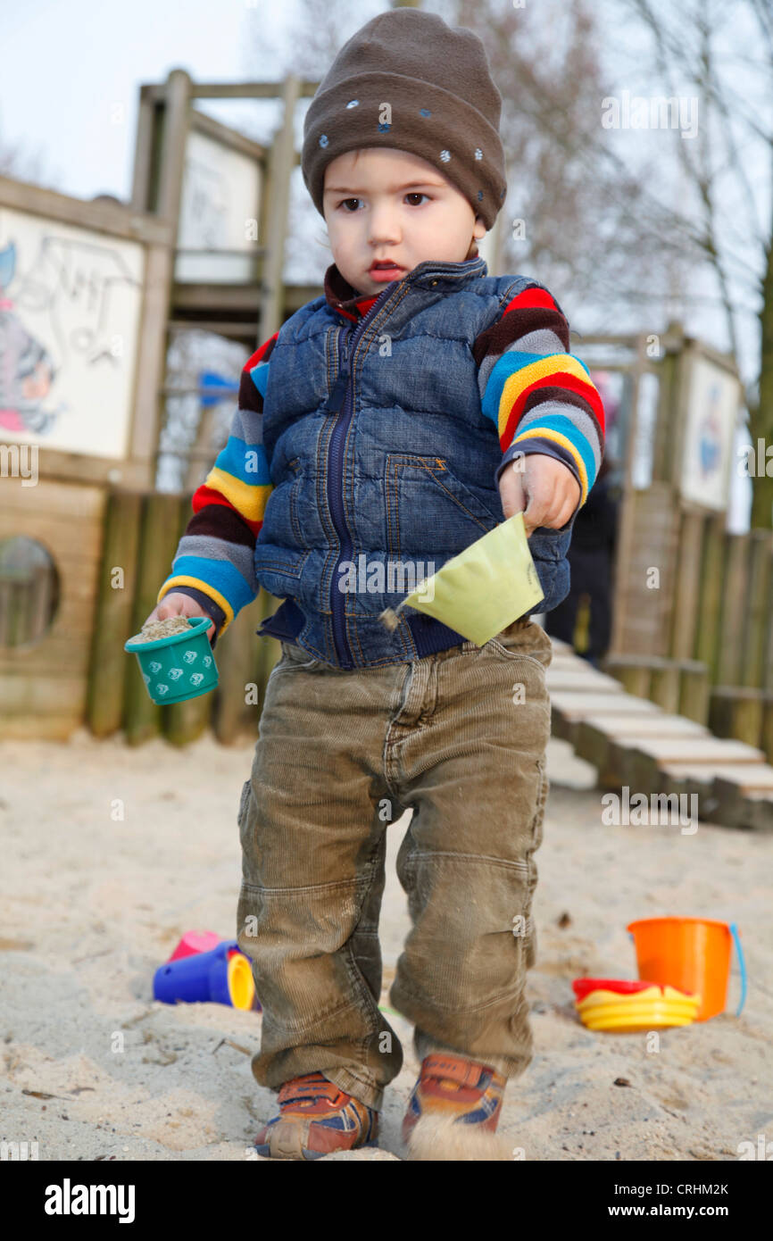 little boy playing in a sandpit with sand moulds Stock Photo