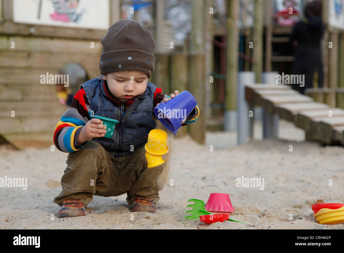 little boy playing in a sandpit with sand moulds Stock Photo