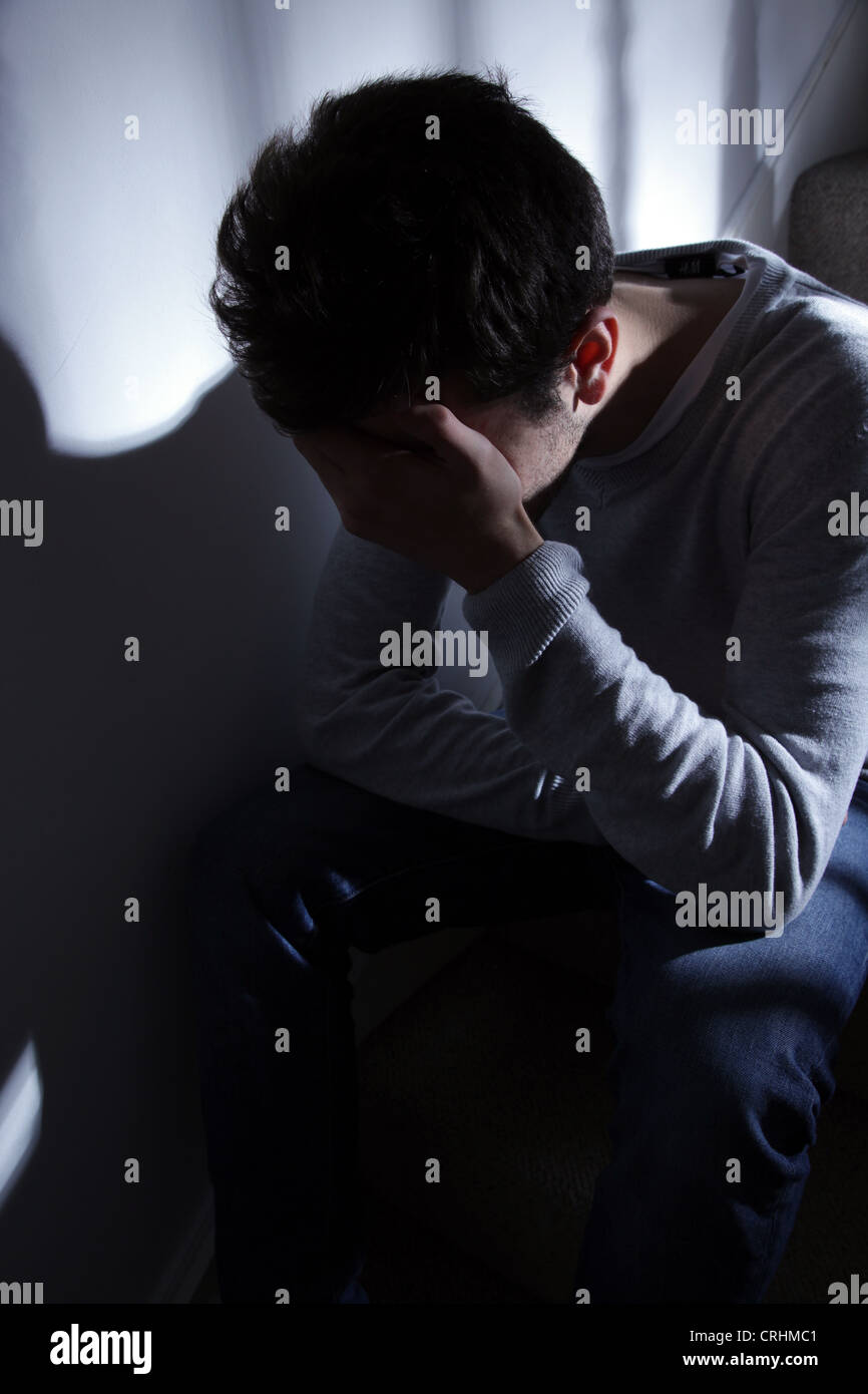 Young man sitting on the stairs, his hand covering his face. Stock Photo