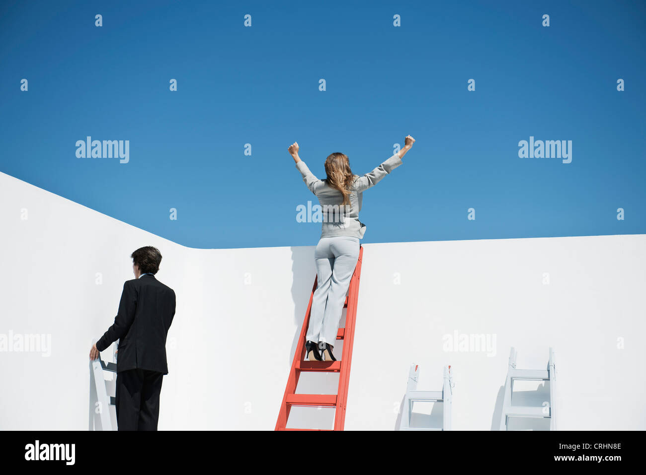 Businesswoman standing at top of ladder with arms raised in air Stock Photo