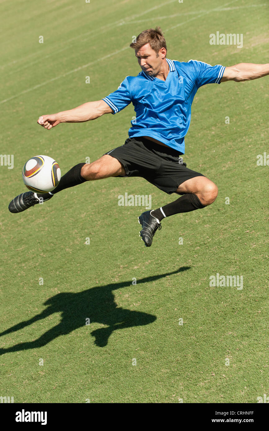 Soccer player kicking ball in midair Stock Photo