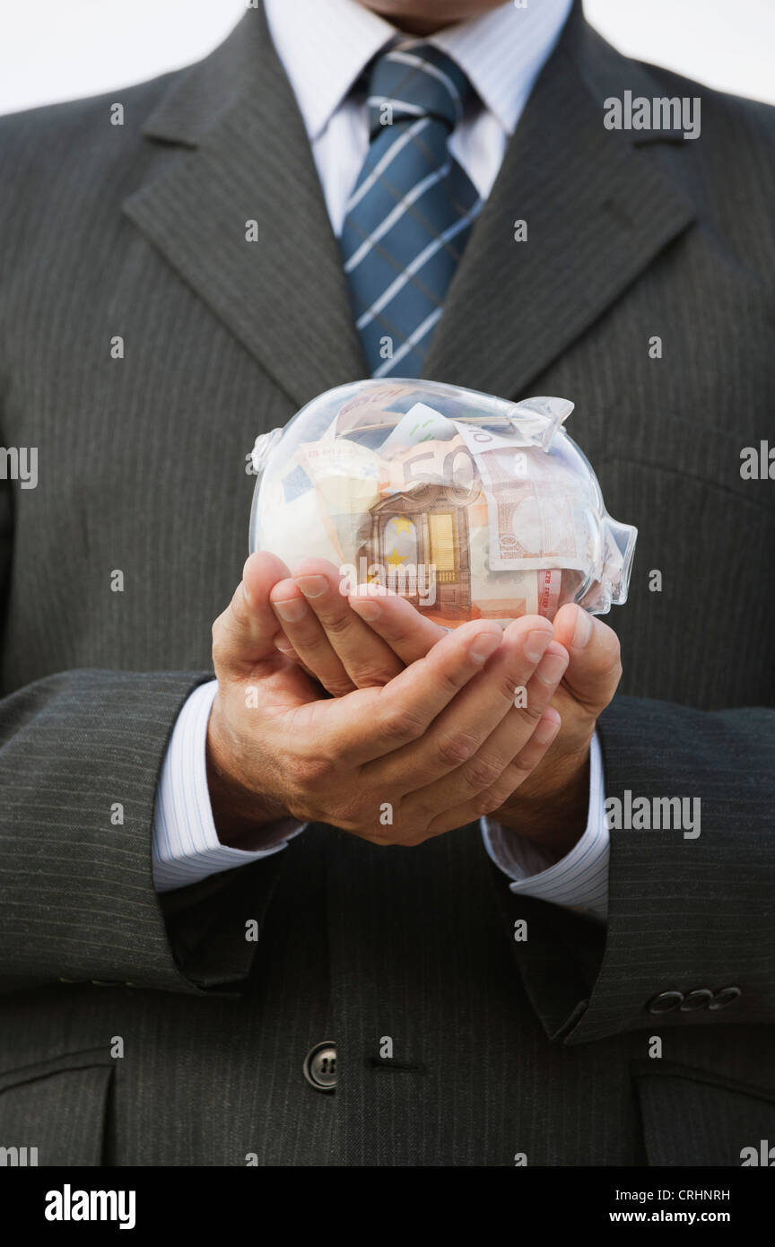 Man holding transparent piggy bank filled with euros, cropped Stock Photo
