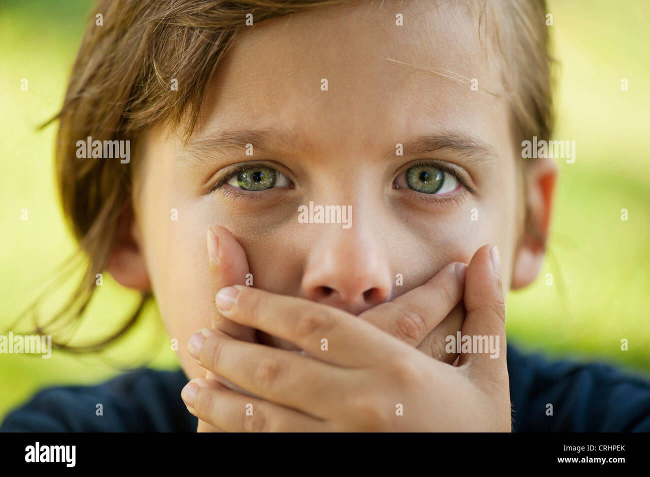 Boy covering mouth with hands Stock Photo