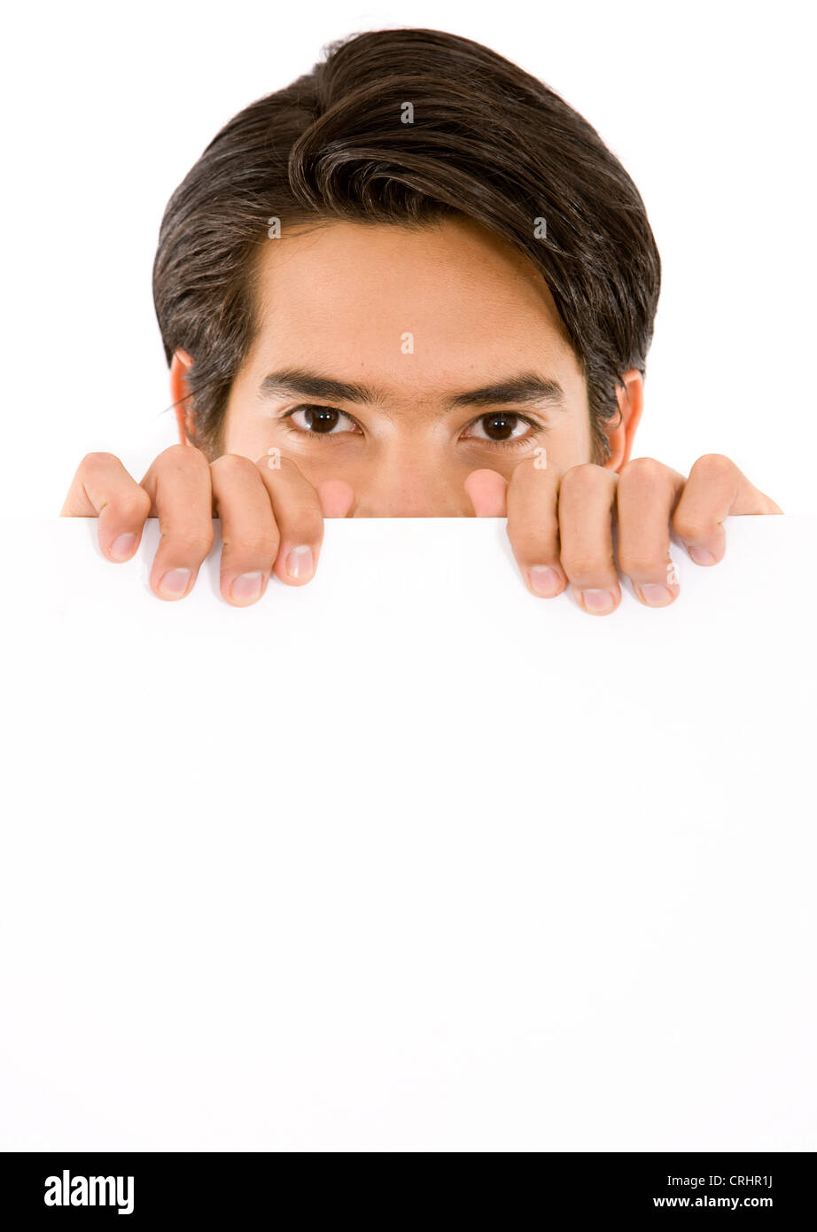 young man peering behind a white sign Stock Photo