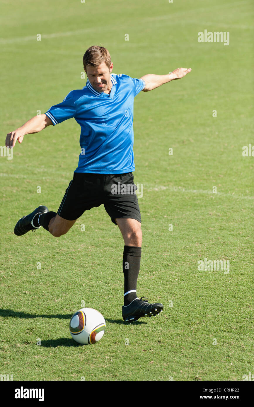 Soccer player kicking soccer ball on soccer field Stock Photo