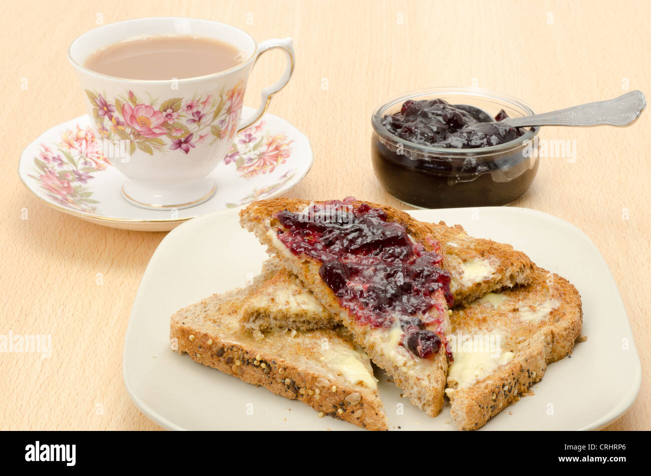 Buttered granary bread toast with jam and a cup of hot tea Stock Photo