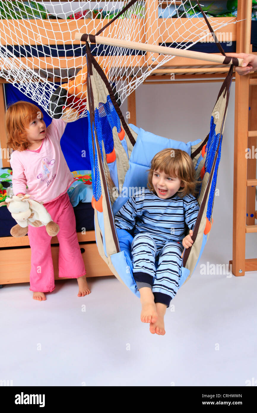 little boy and little girl in pyjama in a swing of Billi-Bolli loft bed Stock Photo