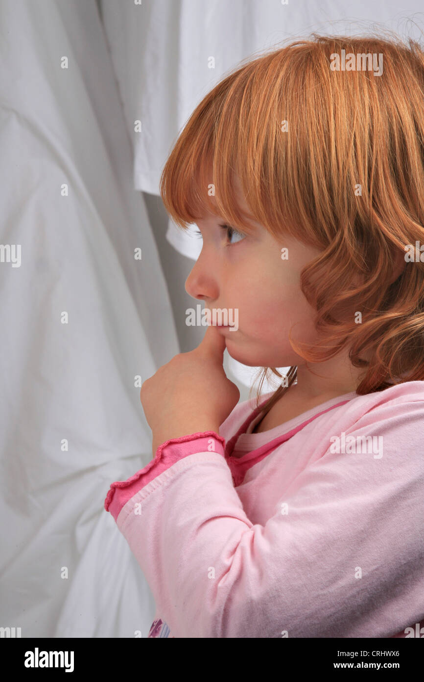 little red-haired girl in pyjama looking dreamy Stock Photo