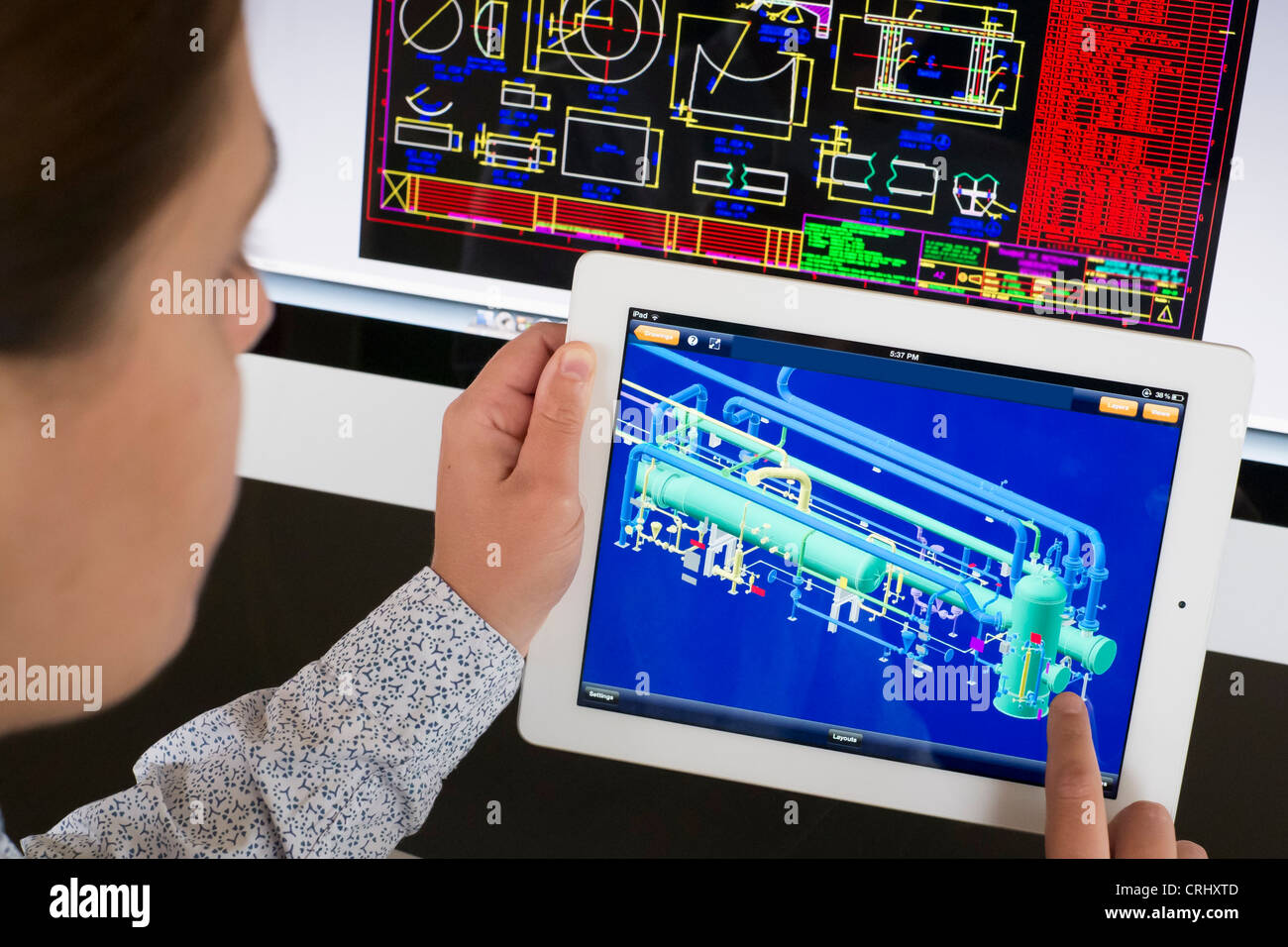 Engineer using iPad Computer Aided Design CAD application to model 3D design of complex industrial design of petrochemical plant Stock Photo
