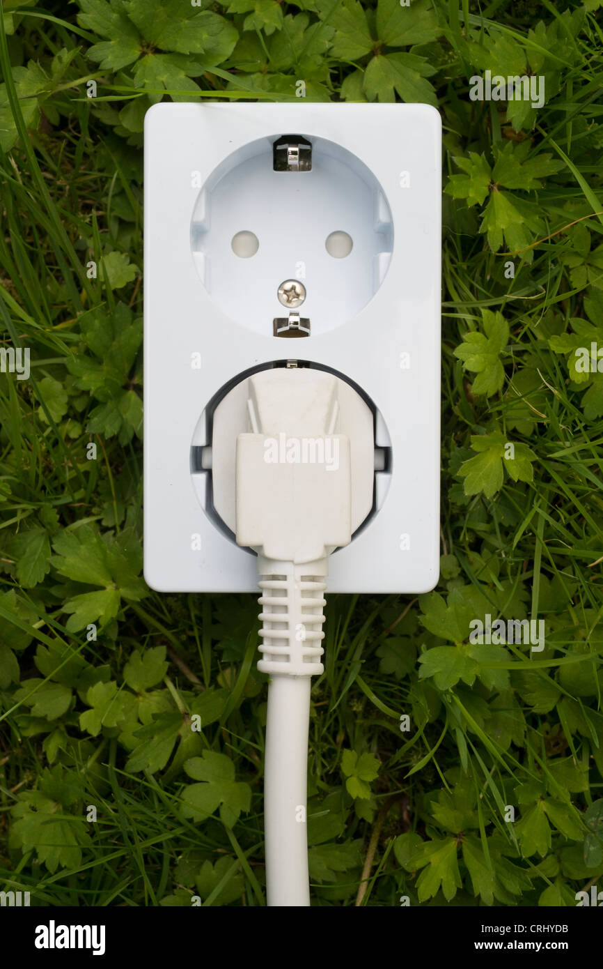 Electric socket on grass concept of green and clean electricity energy supply Stock Photo