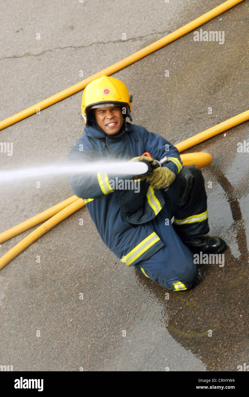 A fire fighter uses a water hose to douse a fire Stock Photo Alamy