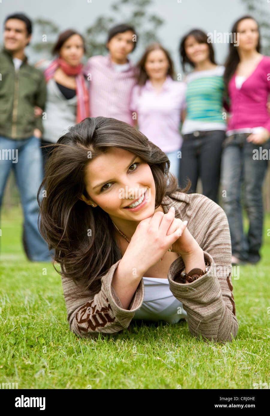 happy group of friends smiling outdoors in a park with a girl in front ...
