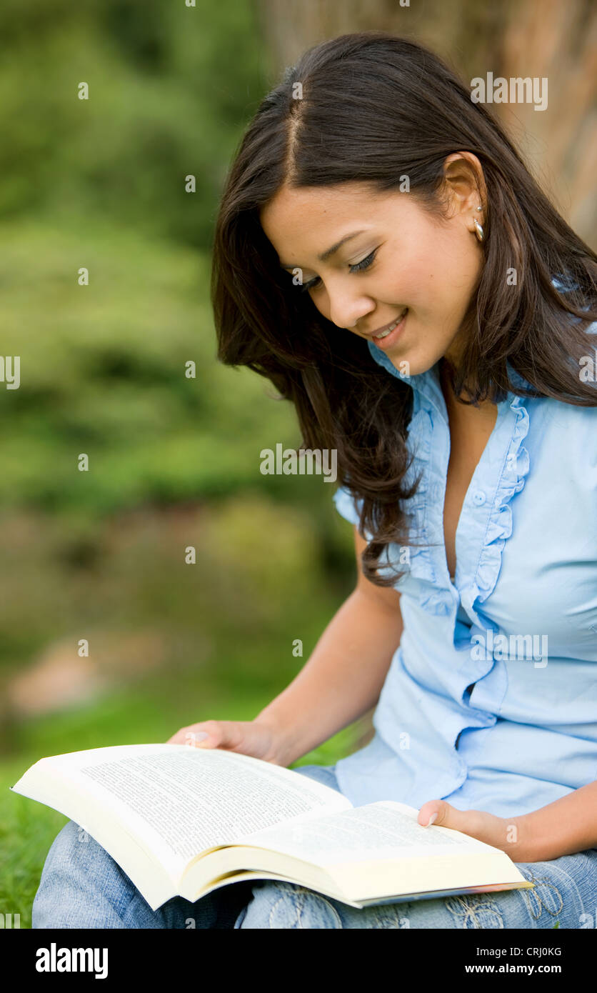young woman sitting in park reading a book Stock Photo - Alamy
