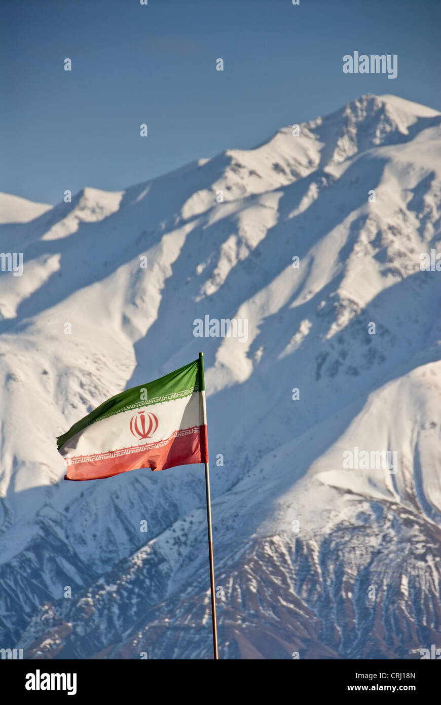 Iranian flag in front of the snowed Alborz mountain range, Alamut, Iran Stock Photo