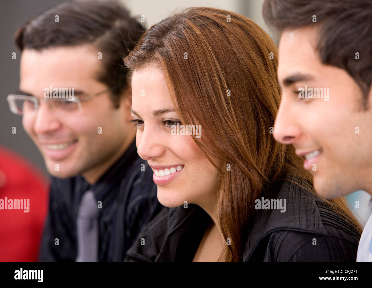 smiling young woman flanked by two young men Stock Photo
