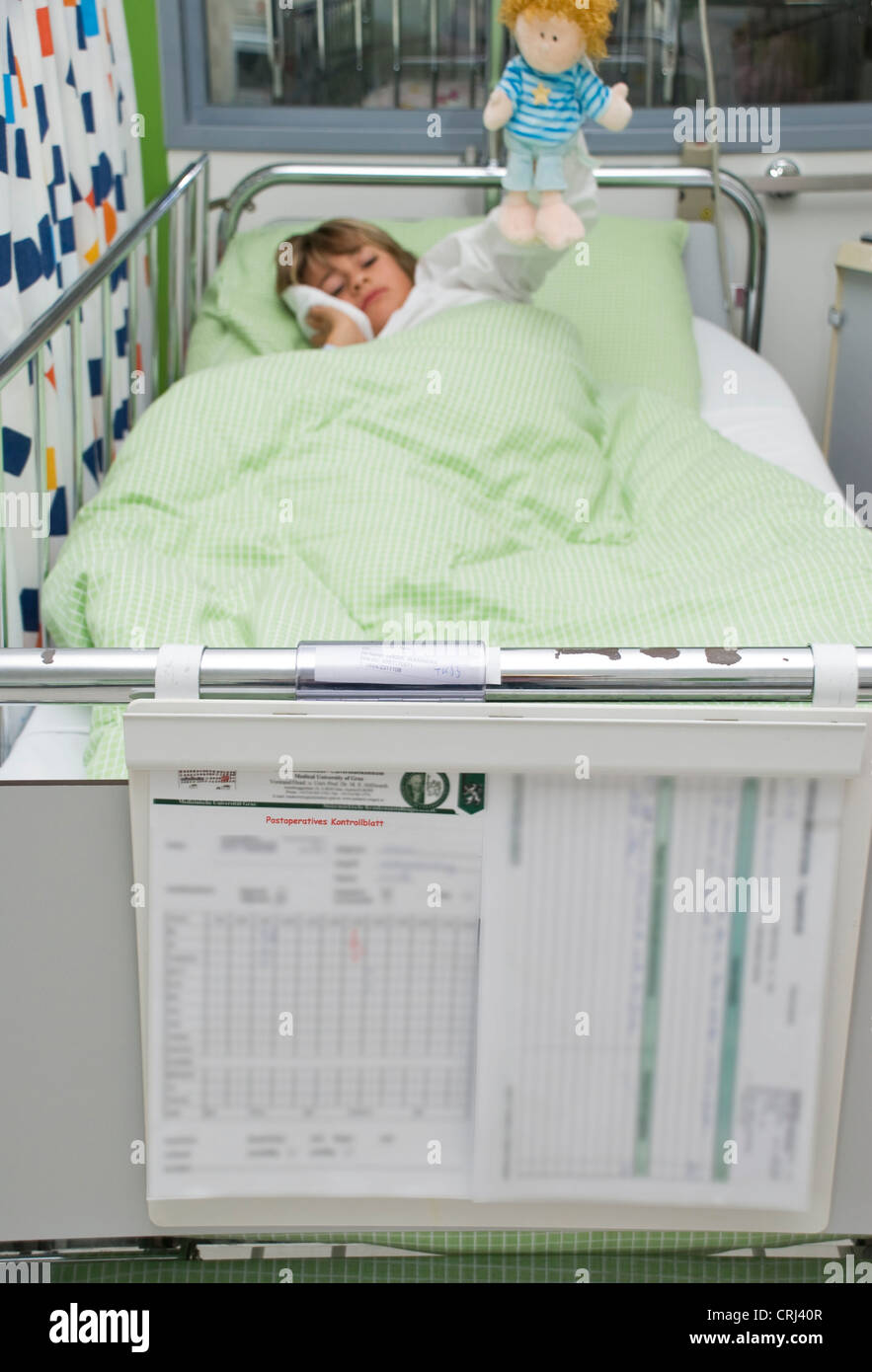 10 years old boy lying in a bed of a children hospital  cooling his cheek Stock Photo