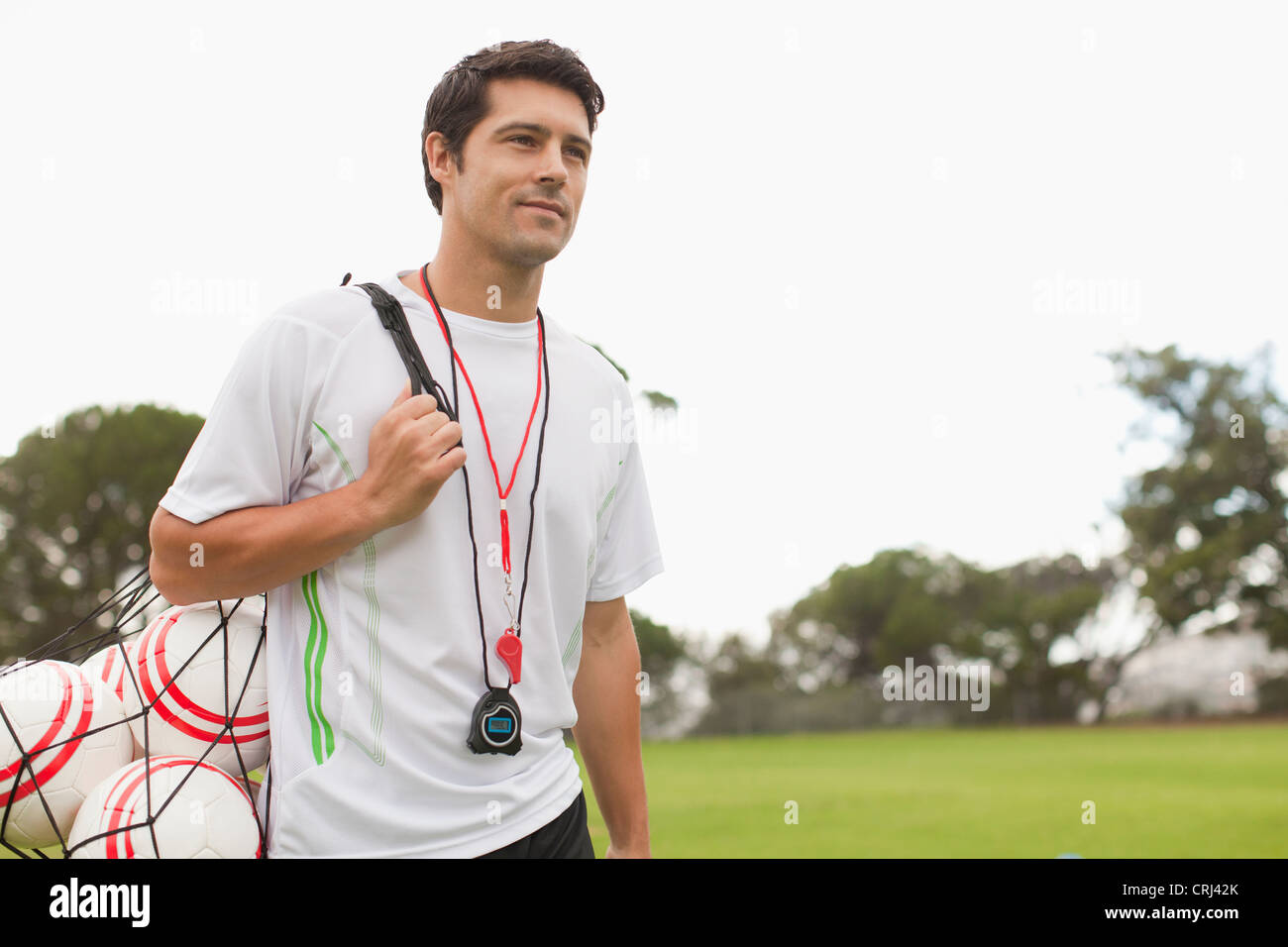 Coach carrying soccer balls on pitch Stock Photo Alamy