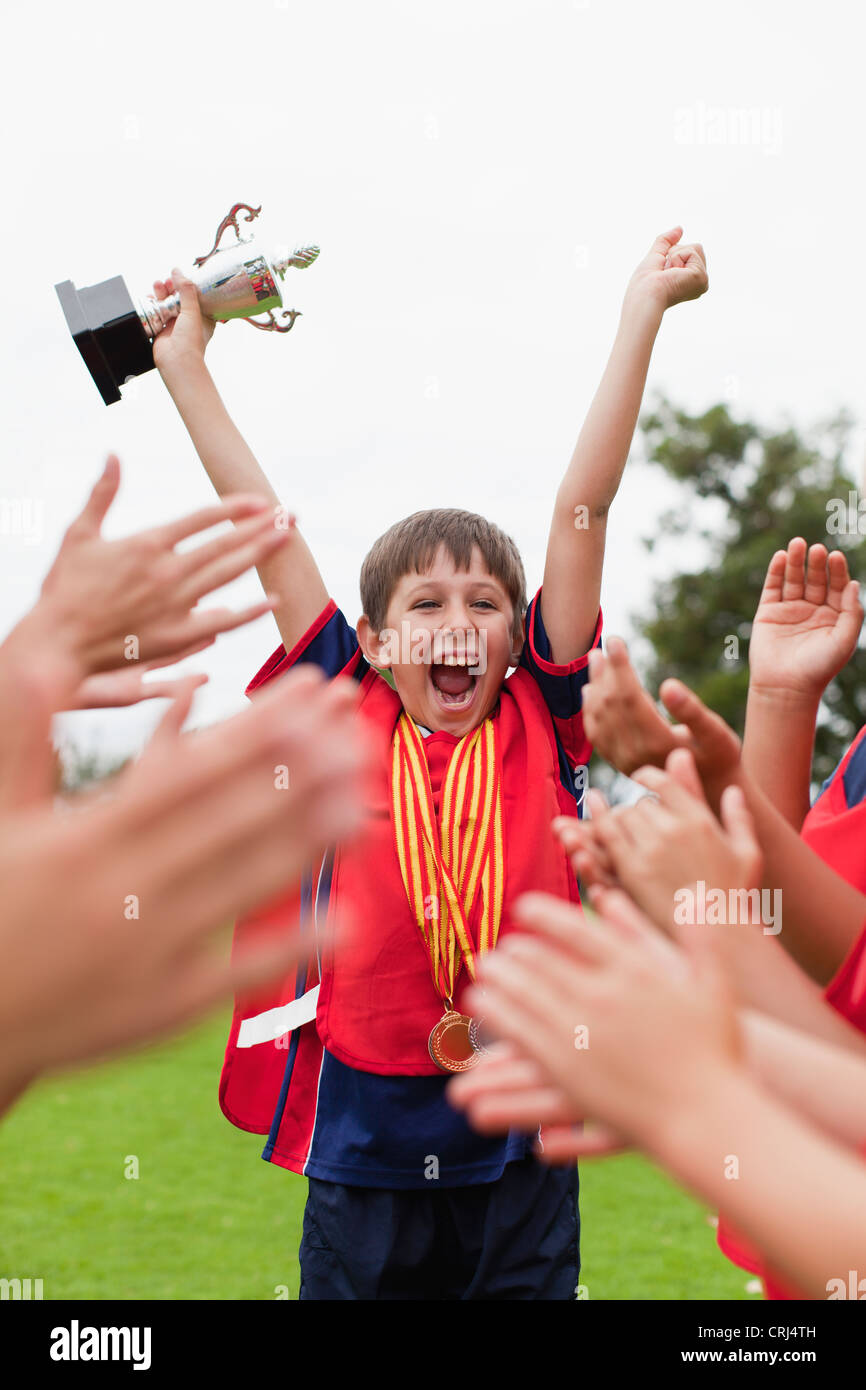 Children cheering teammate with trophy Stock Photo