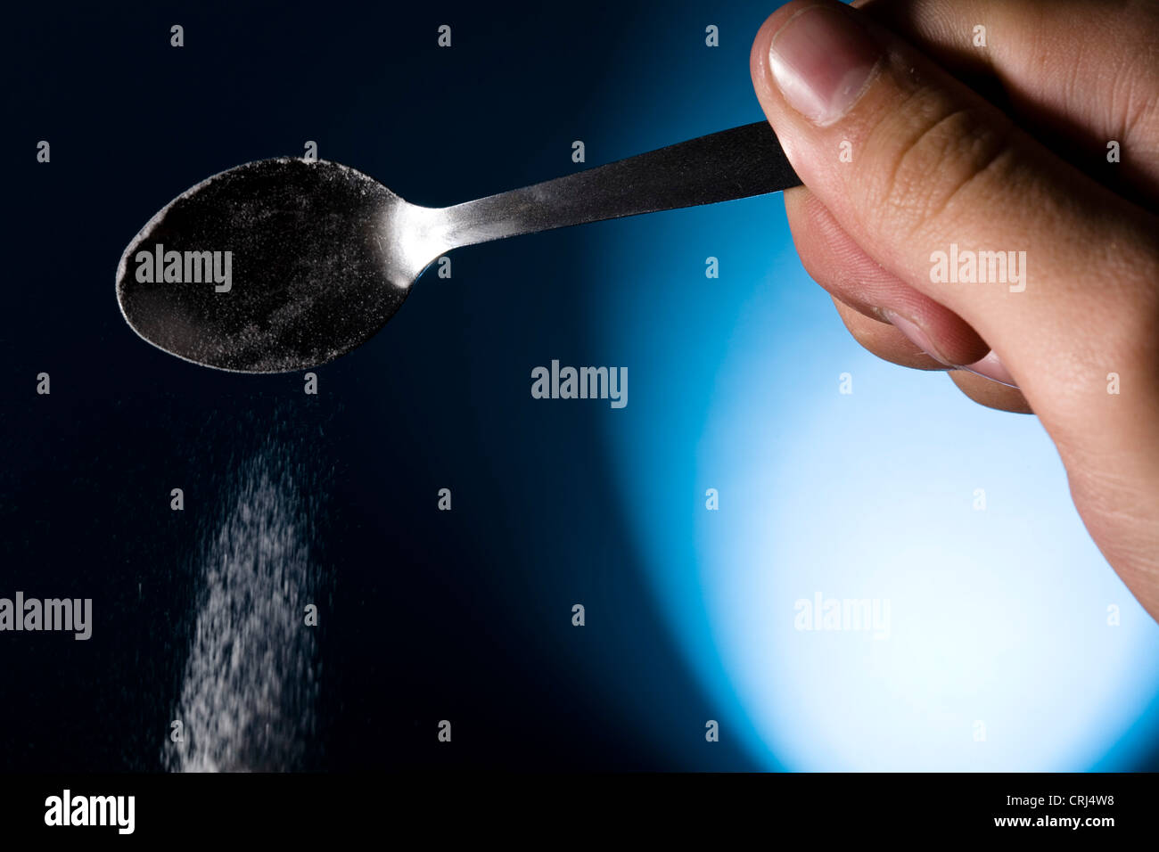 Salt spilling out from a spoon. Stock Photo
