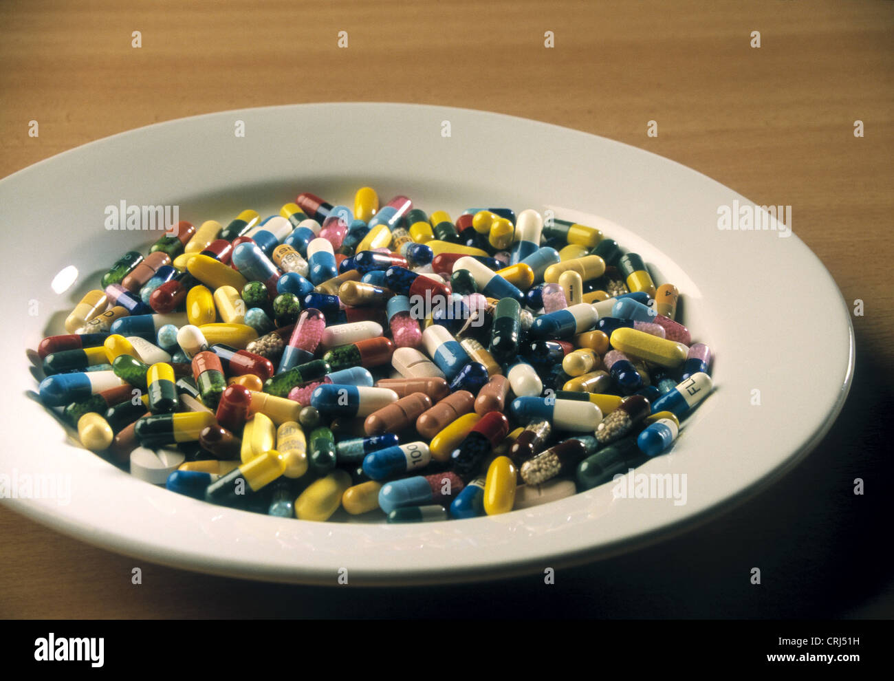 A plate full of tablets and capsules in a variety of colors and sizes Stock Photo