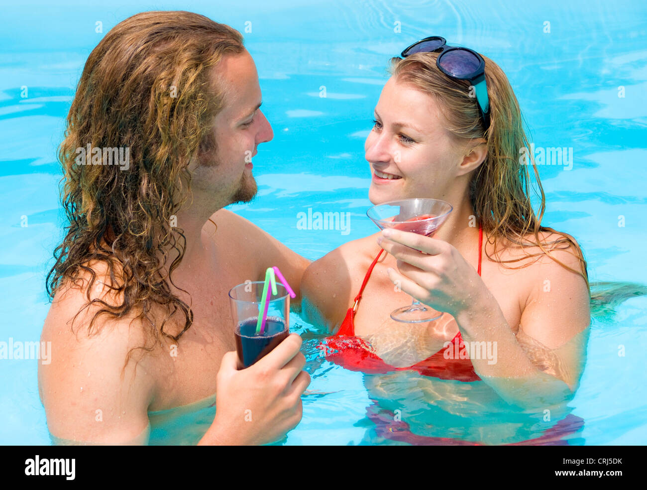 young pair in the pool with drinks Stock Photo