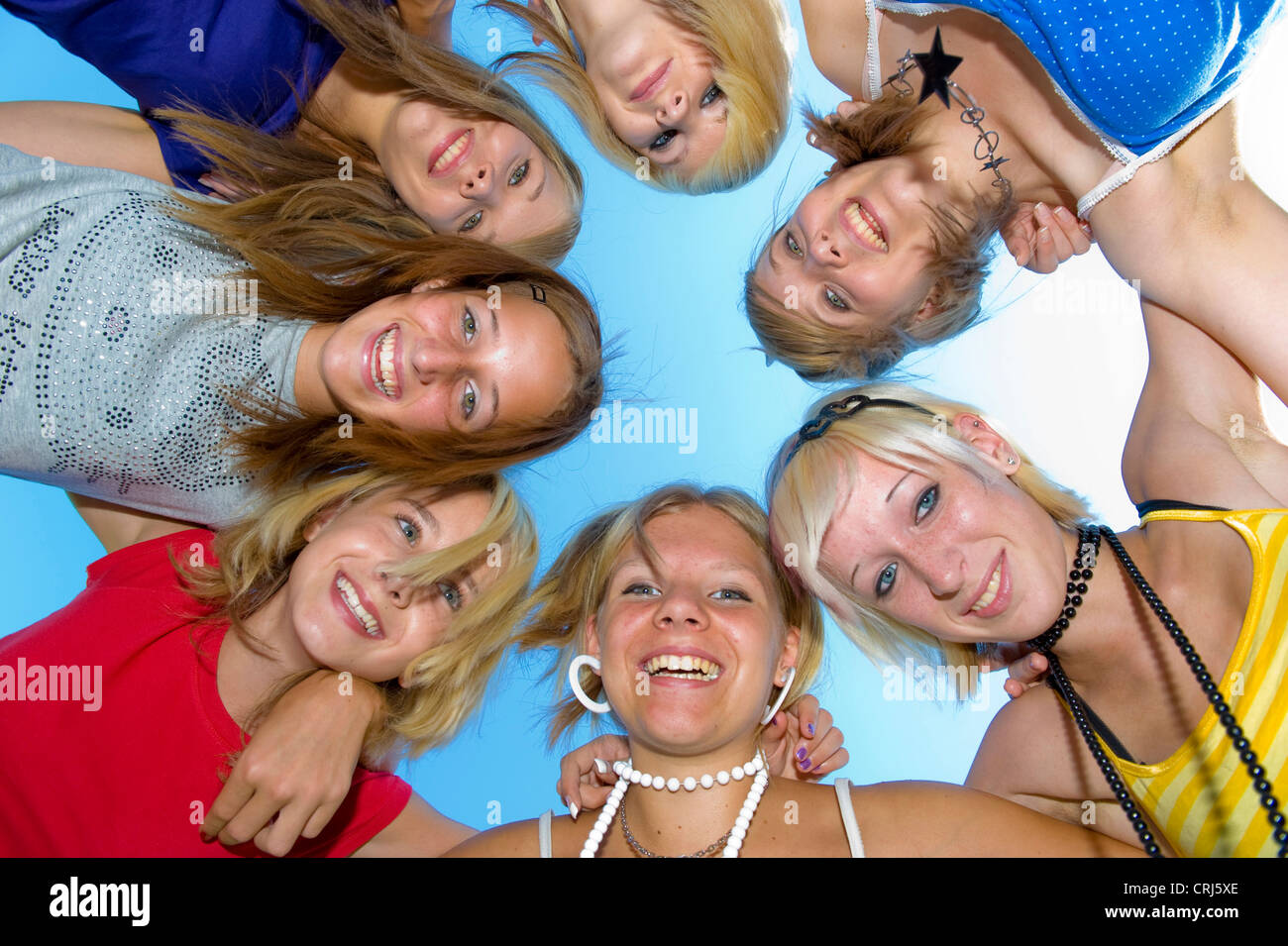 7 teenage girls in a circle holding eachother by the shoulders, putting