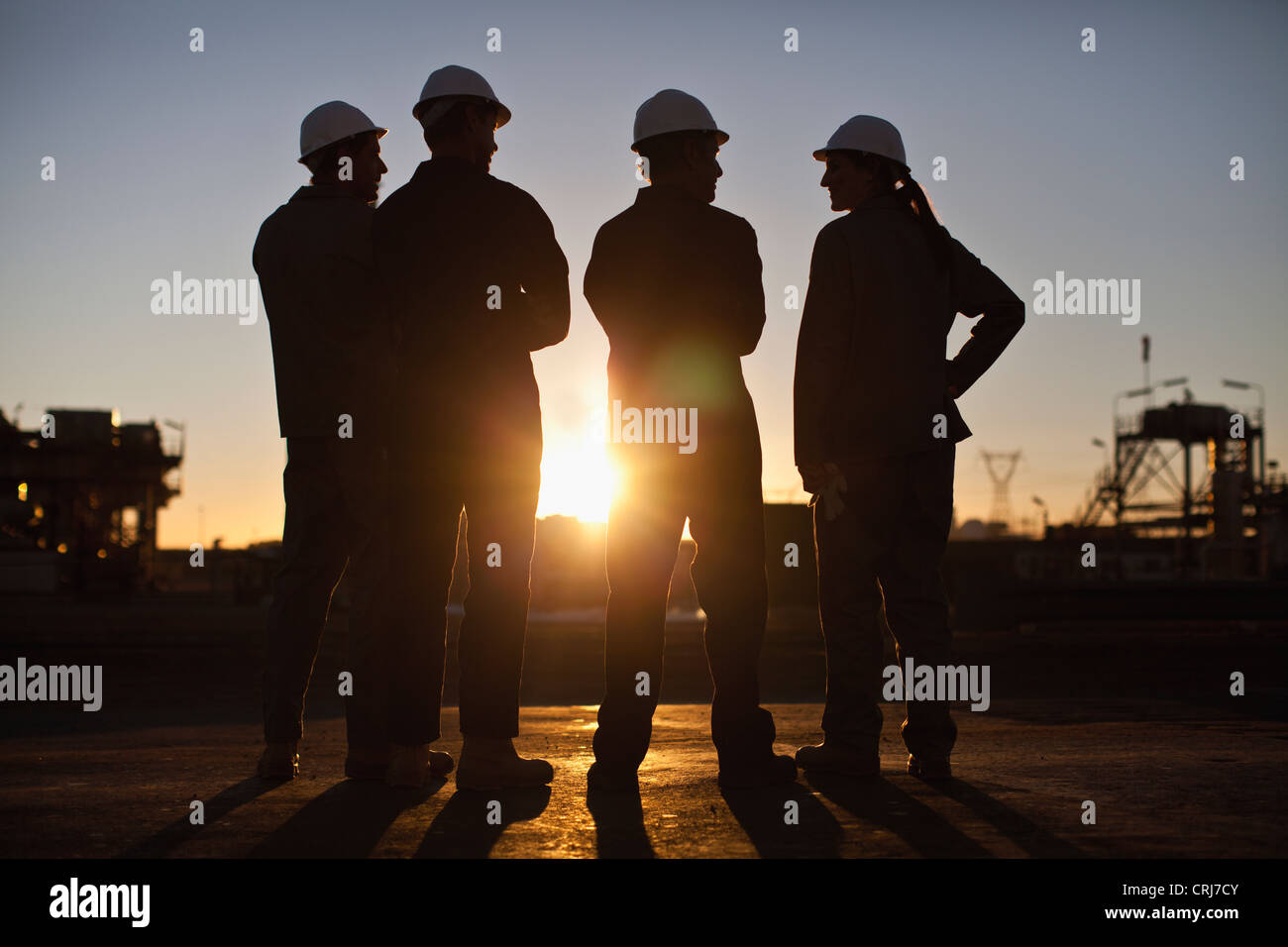 Silhouette of workers at oil refinery Stock Photo