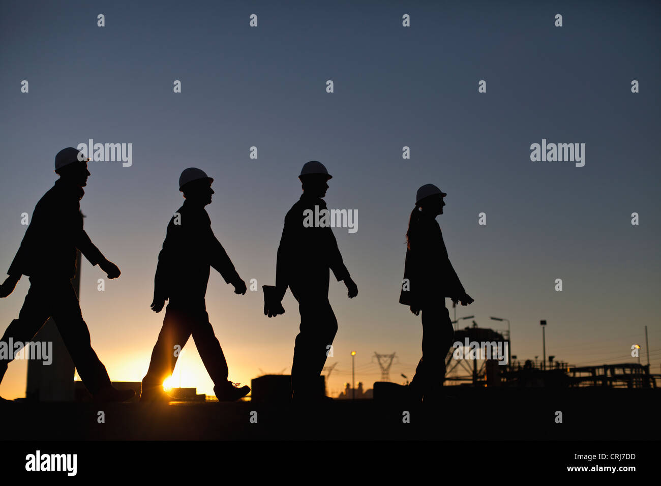 Silhouette of workers at oil refinery Stock Photo