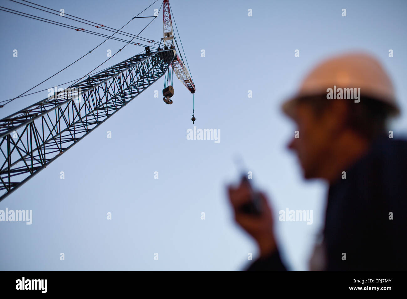 Crane over worker at oil refinery Stock Photo