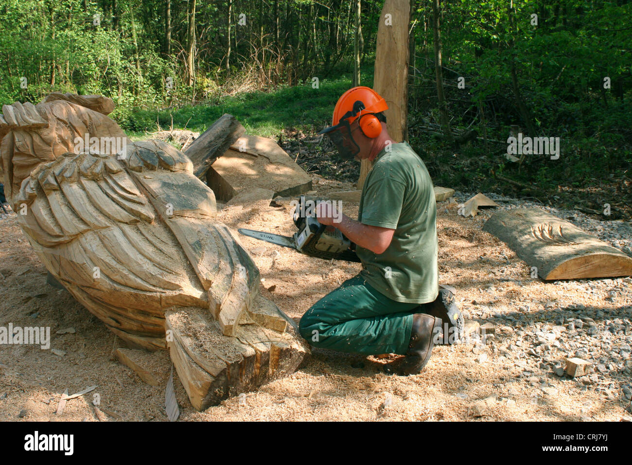 wood carver working on a big owl with a motor saw Stock Photo
