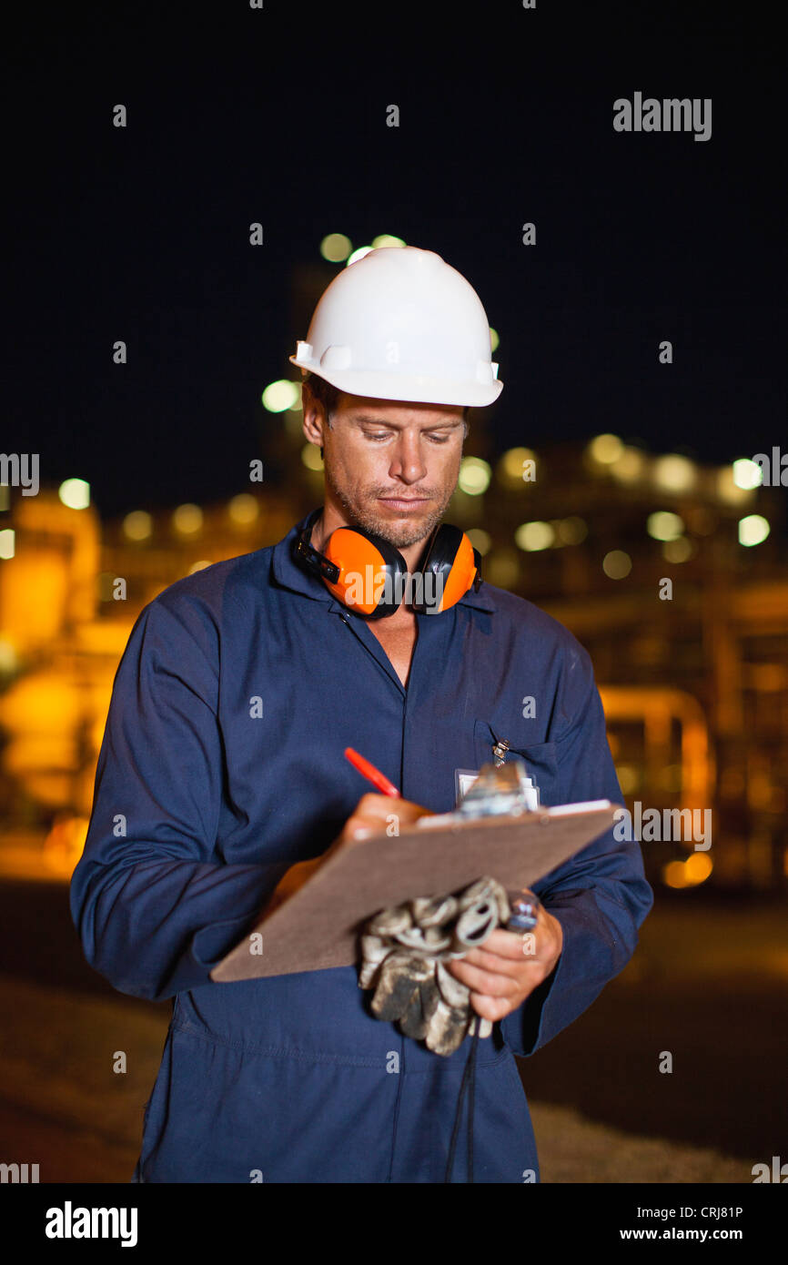 Worker with clipboard at oil refinery Stock Photo