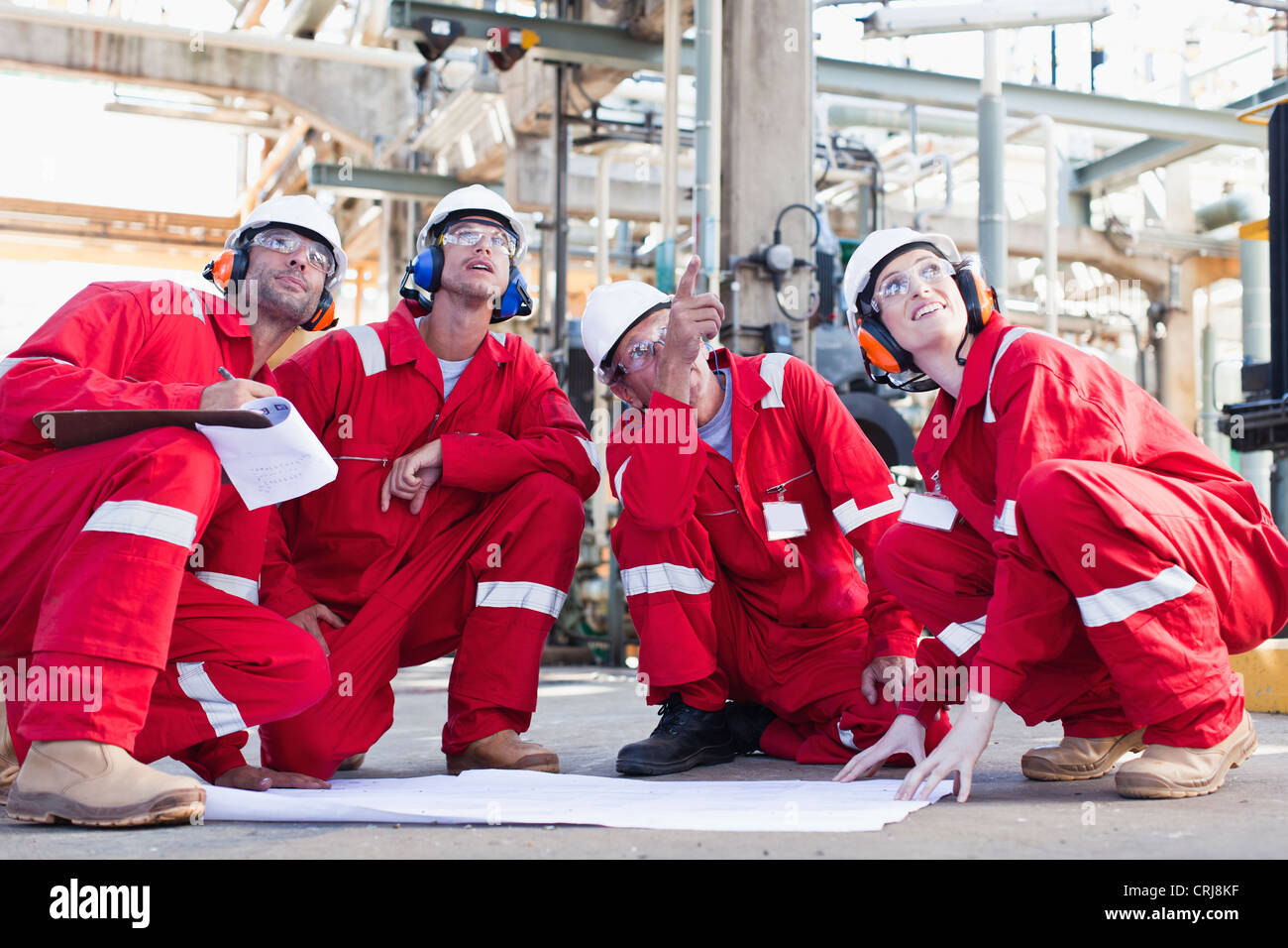 Workers with blueprints at oil refinery Stock Photo