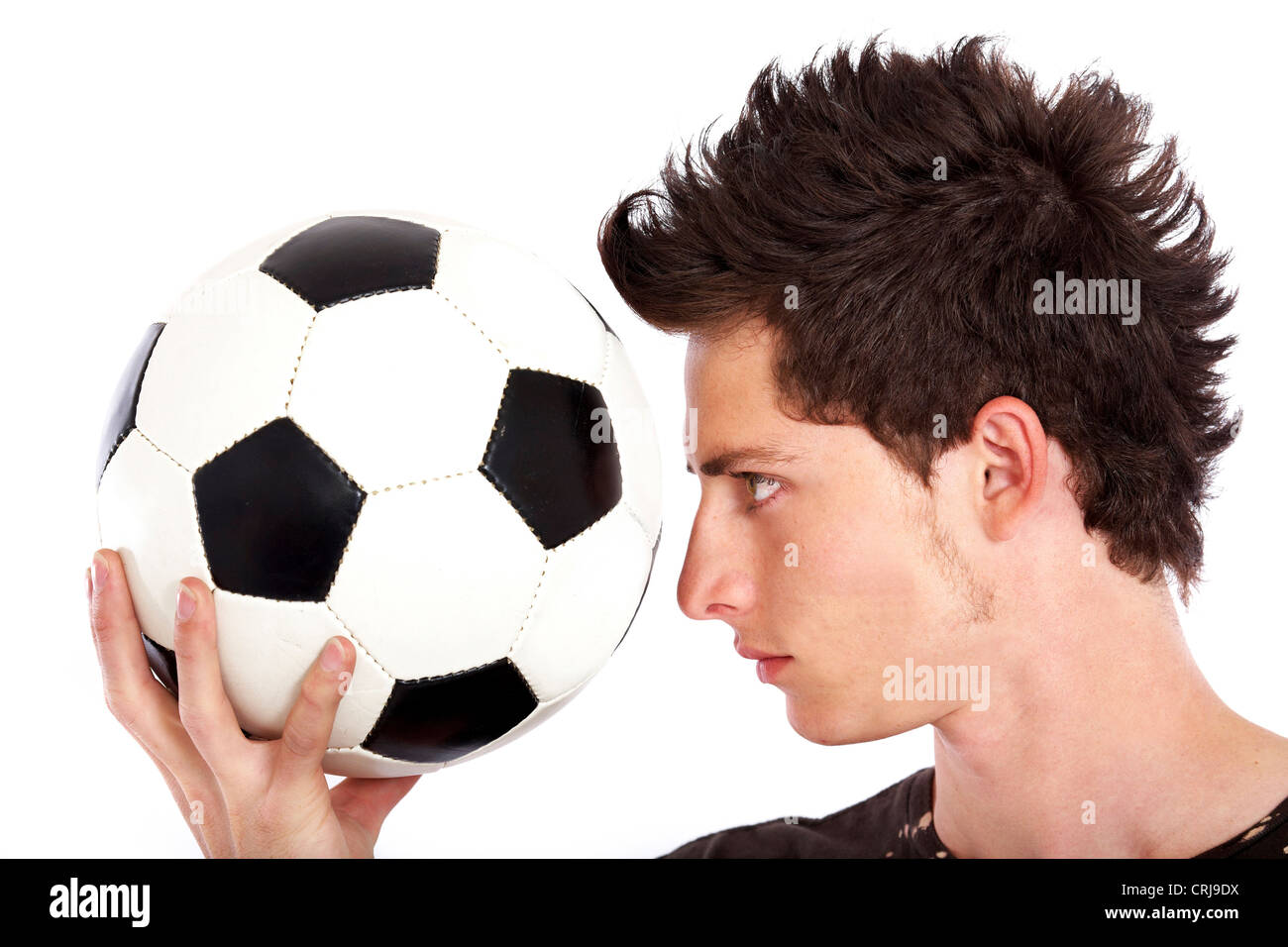 young soccer player holding a ball in front of his face and eying it Stock Photo