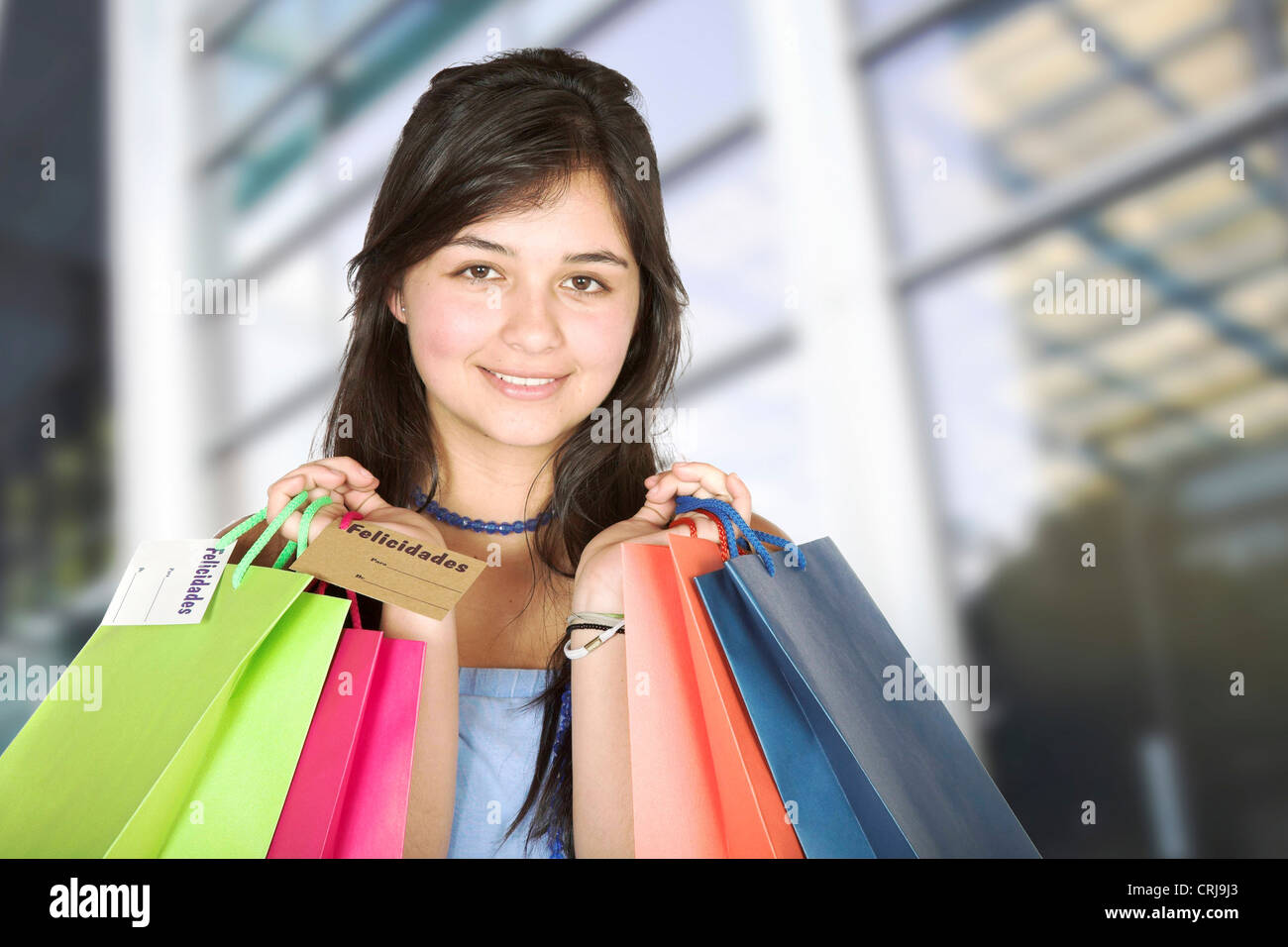 young girl in front of shopping centre holding up shopping bags with a ...