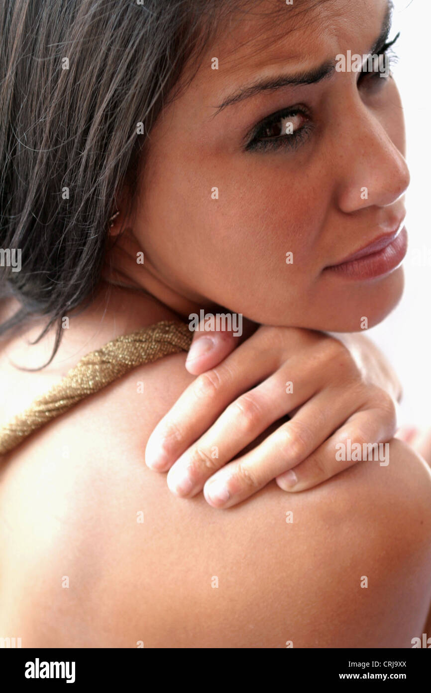 young woman holding her shoulder with a painful look Stock Photo