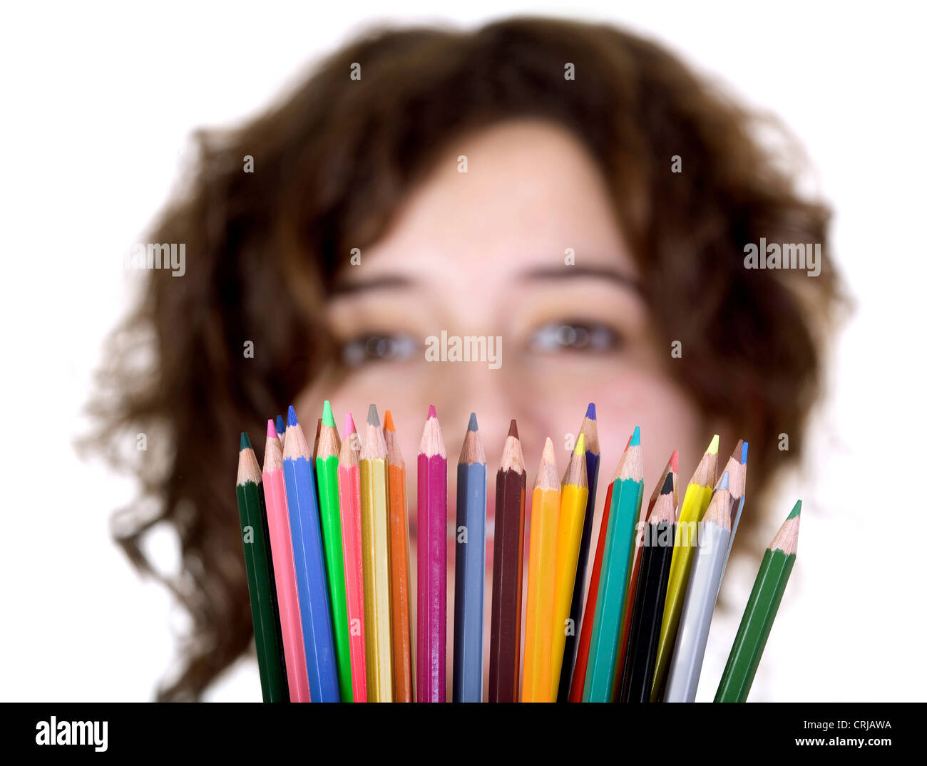young girl looking over a fan of colourful pencils she is holding in front of her Stock Photo