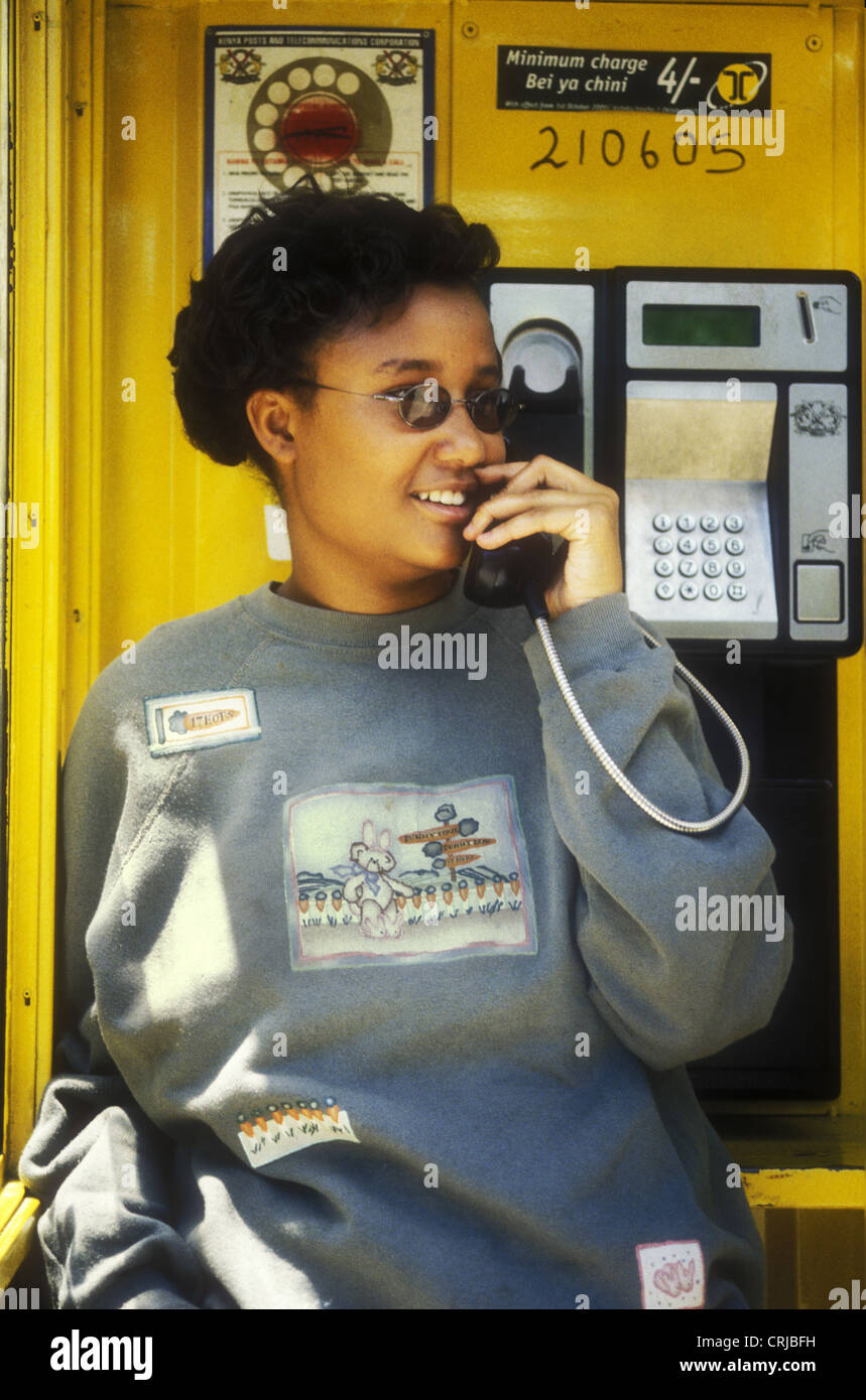 Young Africa woman talking on telephone in call box Nakuru Kenya She is smiling wearing western clothes Stock Photo